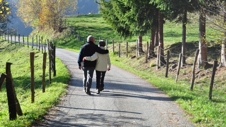 An older couple walking arm in arm along a country path